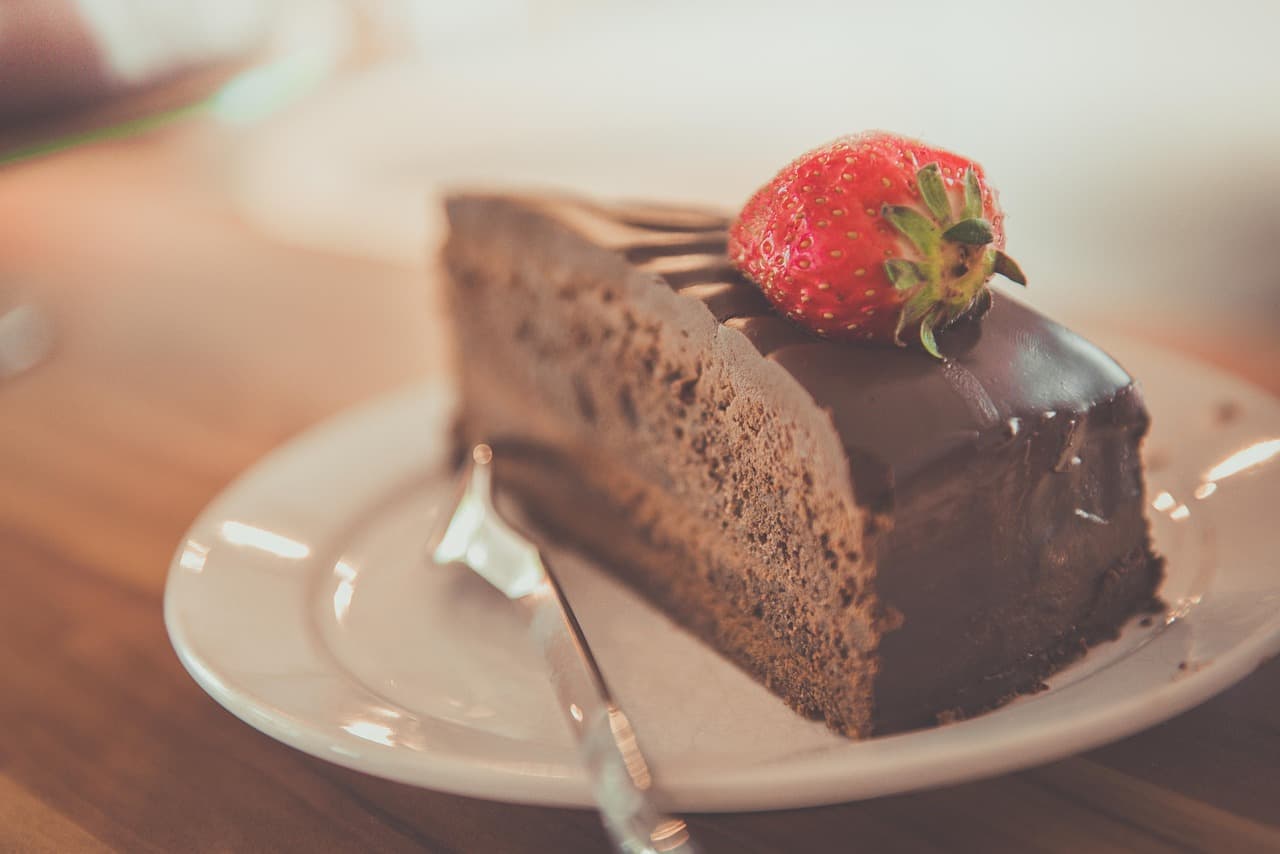 A slice of chocolate cake with strawberry on a cafe plate.
