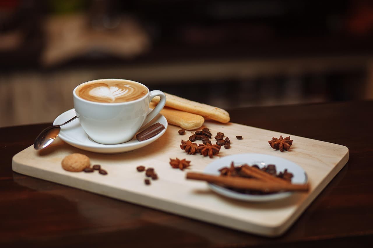 Latte served with cinnamon, star anise, and coffee beans.