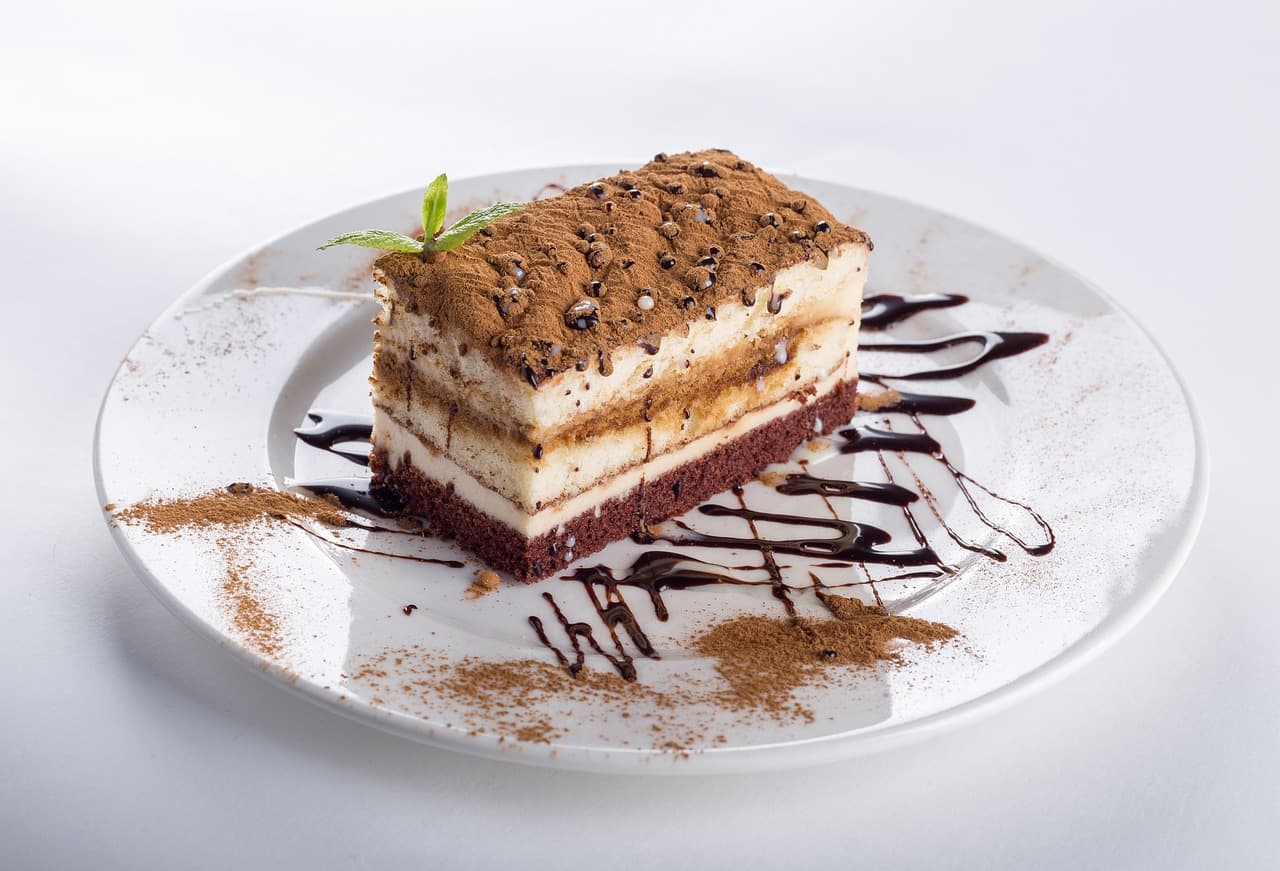 Tiramisu slice with cocoa dust and chocolate drizzle.